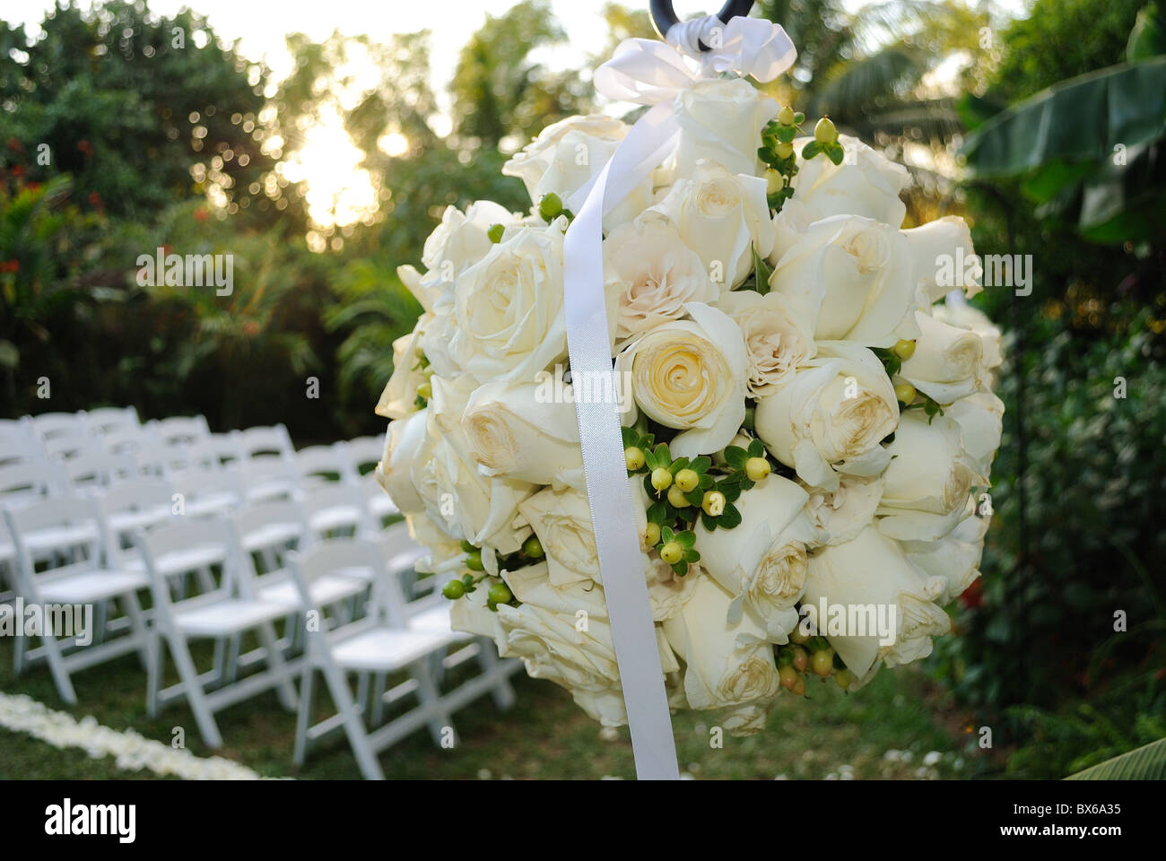 Un bouquet di fiori con rose di fronte sedie in fila ad una cerimonia di nozze Foto Stock