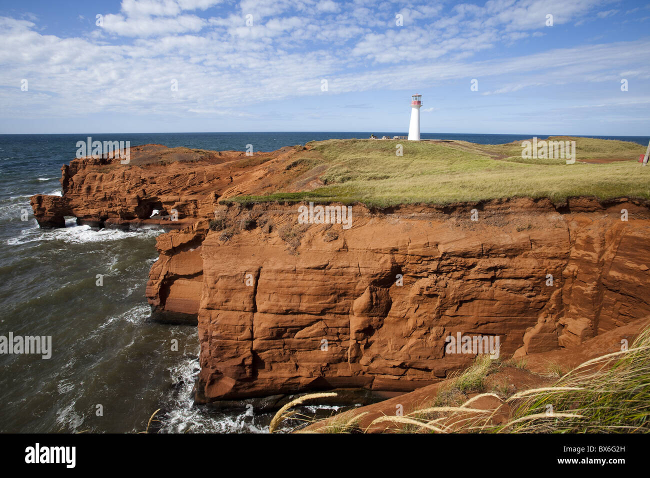 Pietra arenaria rossa cliff e faro di Cap-aux-Meules isola sull'Iles de la Madeleine (Maddalena isole), Quebec, Canada Foto Stock