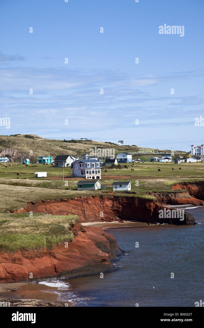 Festone rosso scogliere di arenaria con case appollaiato sulla cima dell'isola di Havre-Aubert, Iles de la Madeleine, Quebec, Canada Foto Stock
