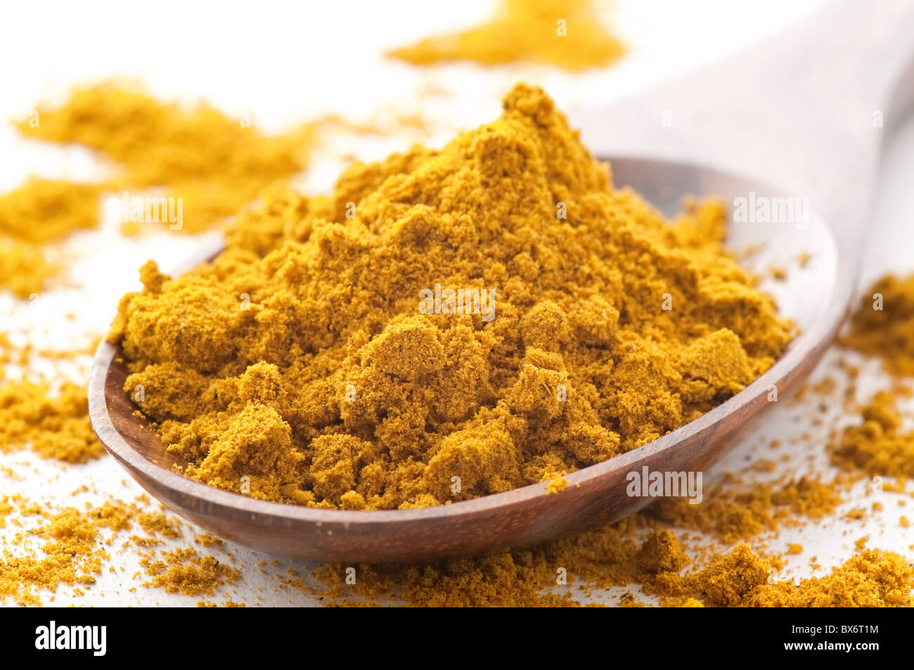 Curry in polvere come mix di spezie su un cucchiaio di teak su sfondo bianco Foto Stock