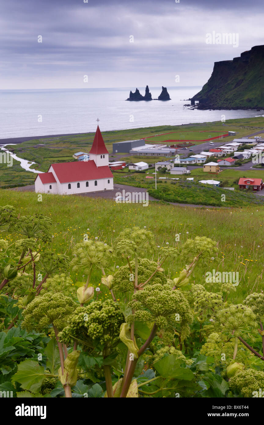 La chiesa ed il villaggio di Vik (Vik un Myrdal) e mare Reynisdrangar pile in distanza, costa sud dell'Islanda (Sudurland), Islanda Foto Stock