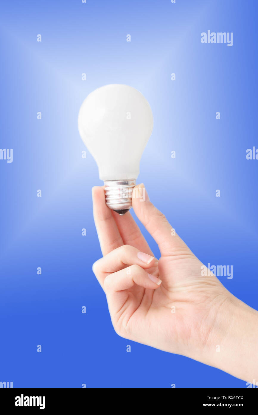 La mano di una persona in possesso di una lampadina nella parte anteriore di un bianco a gradiente blu. Foto Stock