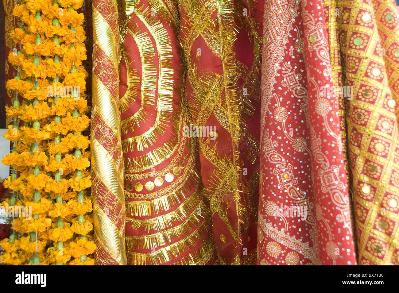 Rosso e oro tinselled panni per devoti indù la visita di un tempio e di calendula ghirlande di fiori, Guwahati, Assam, India, Asia Foto Stock
