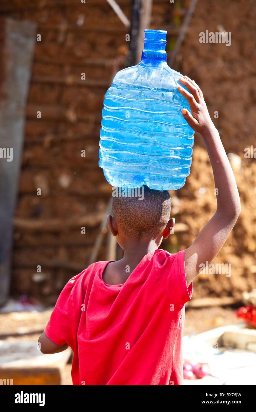 Ragazzo che trasportano l'acqua nella baraccopoli di Kibera, Nairobi, Kenia Foto Stock