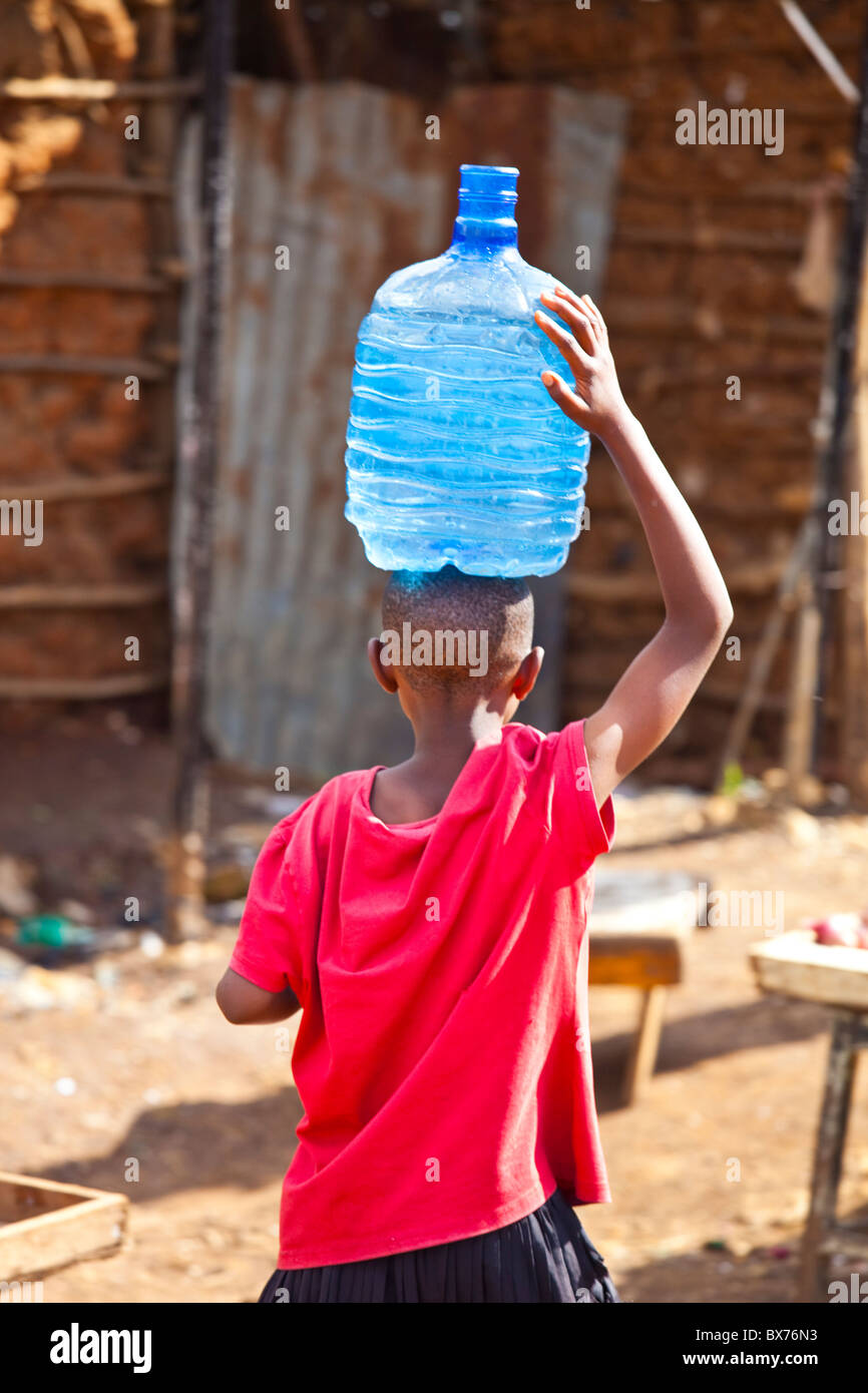 Ragazzo che trasportano l'acqua nella baraccopoli di Kibera, Nairobi, Kenia Foto Stock