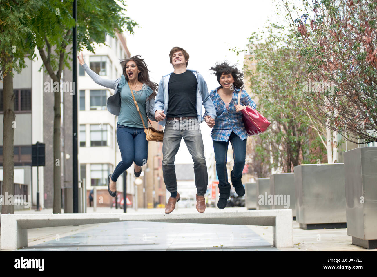 3 giovani saltando in strada Foto Stock