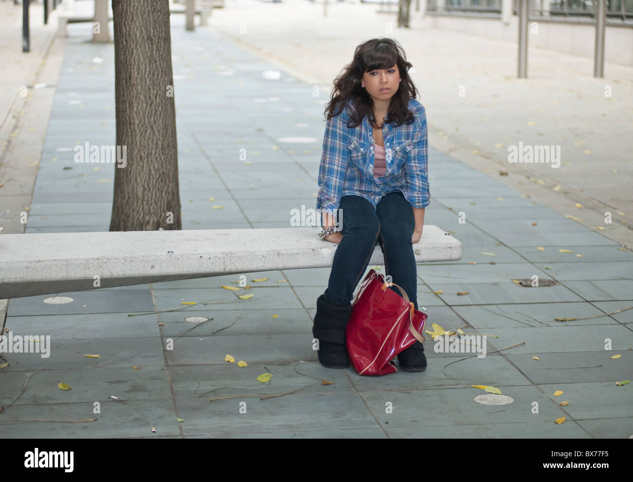 Femmina solitario seduto in strada Foto Stock