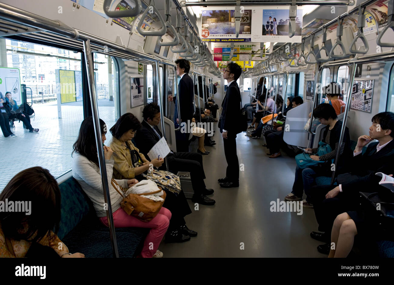 I passeggeri a bordo di equitazione la Yamanote linea loop treno che circonda una maggiore Metropolitan Tokyo, Giappone, Asia Foto Stock