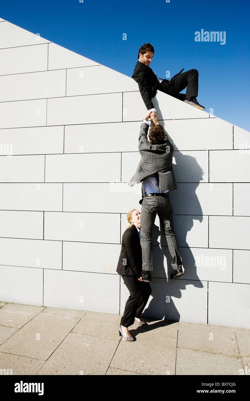 2 persone aiutano l'uomo sulla parete Foto Stock