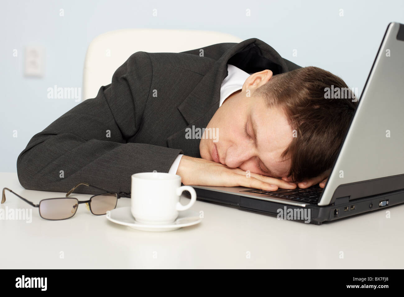 Un giovane imprenditore non abbastanza sonno e si è addormentato sul lavoro Foto Stock
