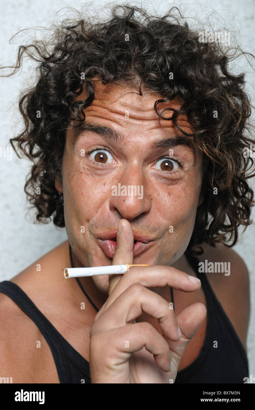 Ritratto di uomo con sigaretta e rendendo shushing gesto Foto Stock