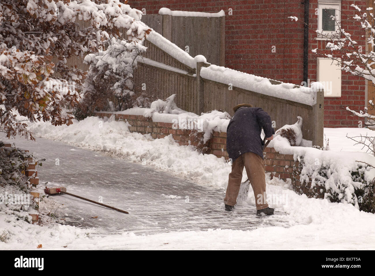 L'uomo deselezionando il suo drive od neve con spade e spazzola Foto Stock