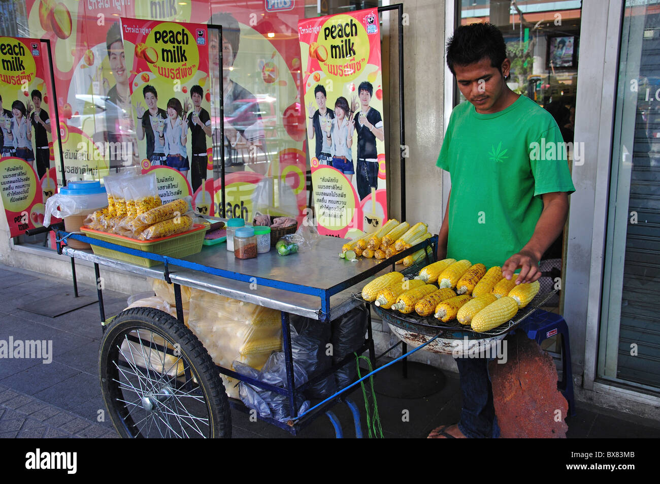 L'uomo vendita di cuocere le pannocchie di granoturco in cibo di strada, di stallo Silom, Bang Rak distretto, Bangkok, Thailandia Foto Stock