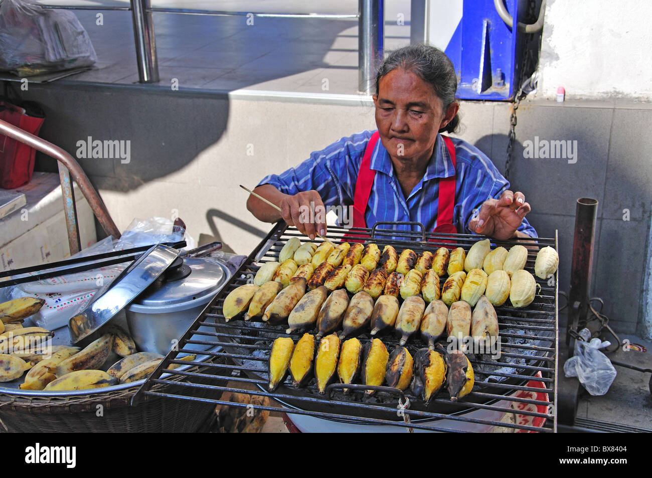 La donna la cottura di banane sul cibo di strada, di stallo Silom, Bang Rak distretto, Bangkok, Thailandia Foto Stock