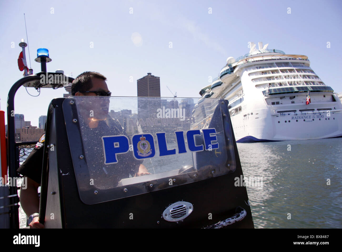 La polizia di Vancouver Unità Marine imbarcazione di pattuglia nei pressi di una nave da crociera nave in Vancouver, British Columbia, Canada Foto Stock