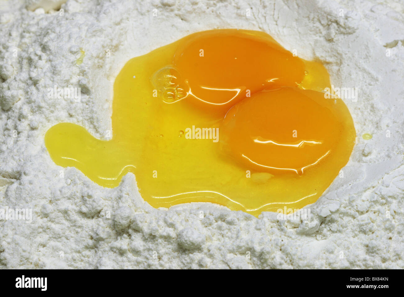 Close up di uova rotte in farina bianca per pasta Foto Stock
