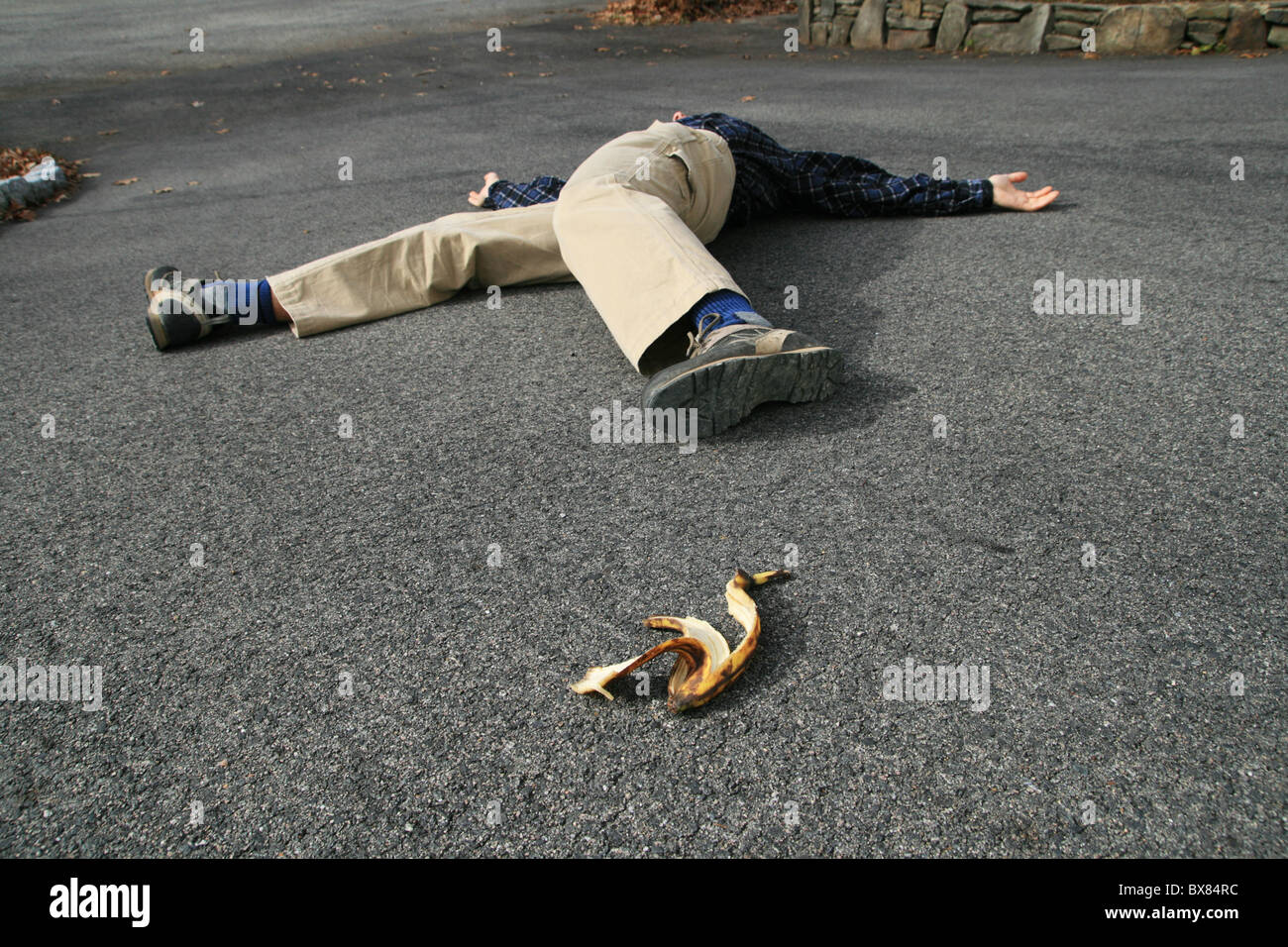 Un uomo che ha avuto un incidente quando è scivolato su una buccia di banana giace a terra Foto Stock