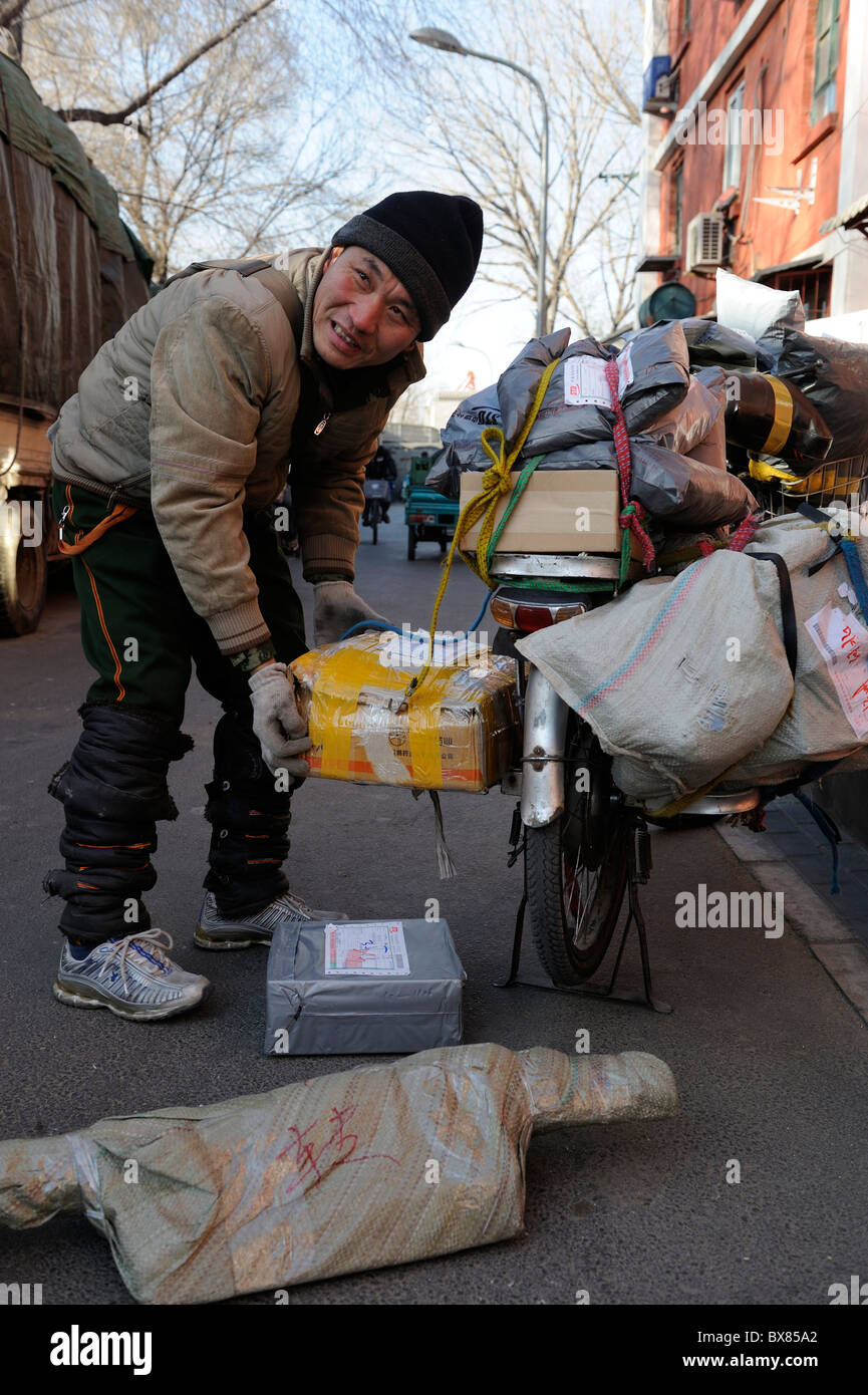 Corriere di Shentong locale Express ricevere pacchetti su un motociclo per essere consegnato a una sottostazione a Pechino in Cina. 11-Dec-2010 Foto Stock