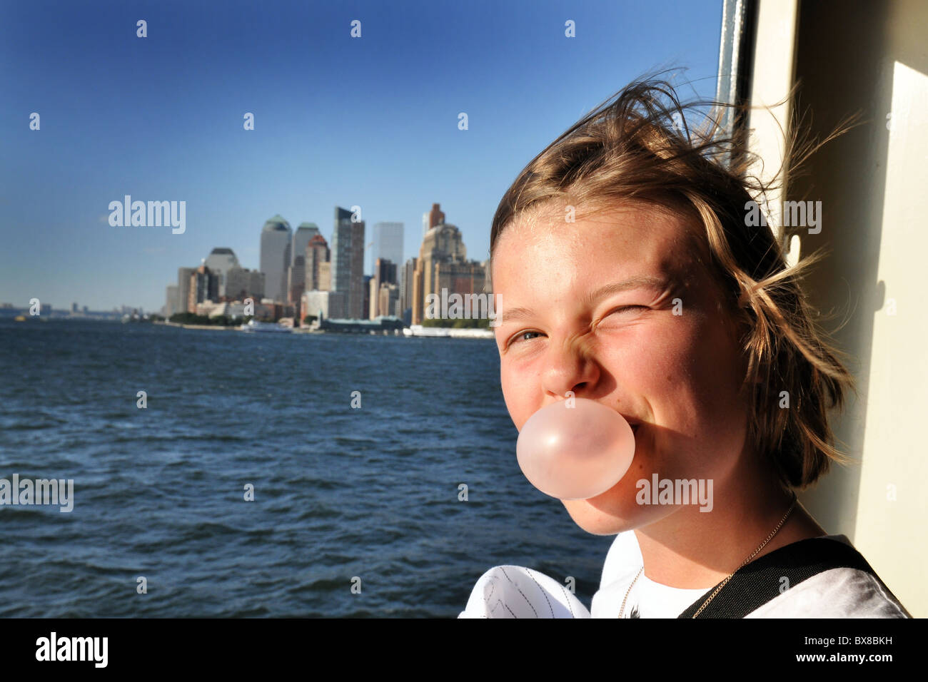 Ragazza adolescente si affaccia sulla New York skyline di Manhattan STATI UNITI D'AMERICA durante lavori di soffiaggio della sua bubblegum. Modello completamente rilasciato/acconsentito Foto Stock