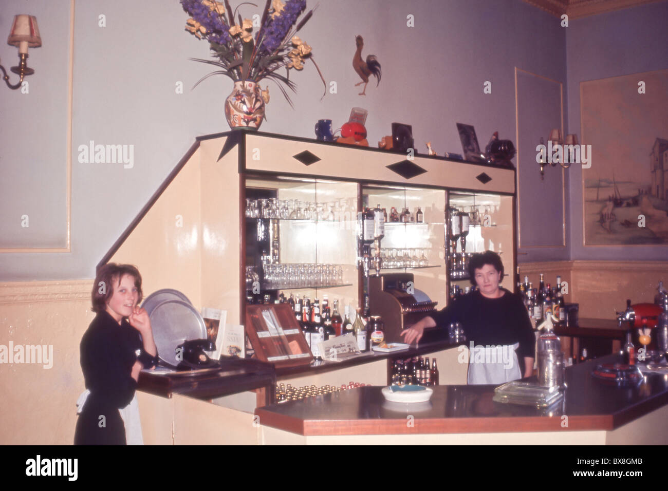 Due cameriere dietro un bar dell'hotel negli anni '1960, che mostrano arredi d'epoca, vetreria e design degli interni dell'ospitalità della metà del secolo. Foto Stock
