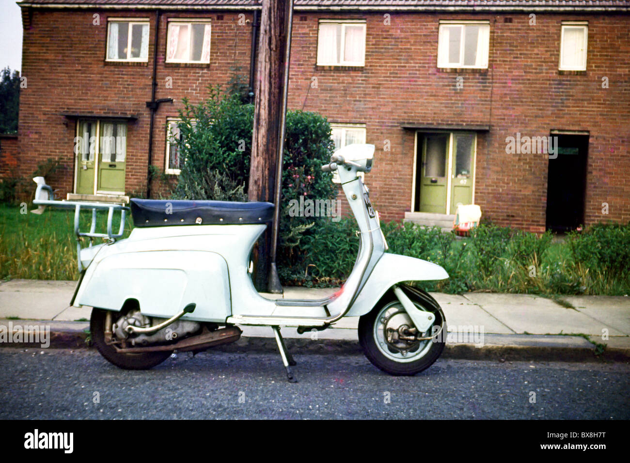 Original 60'simmagine di uno scooter/ciclomotore parcheggiato fino a lato della strada in una terrazza house. Foto Stock