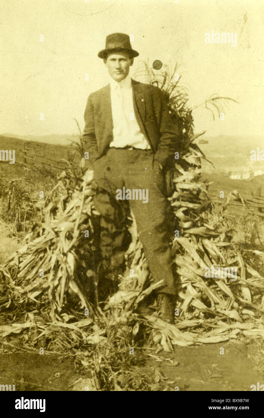 Uomo in piedi accanto a stocchi mais ritratto maschile moda hat nero camicia bianca all'aperto autunno autunno il mais Foto Stock