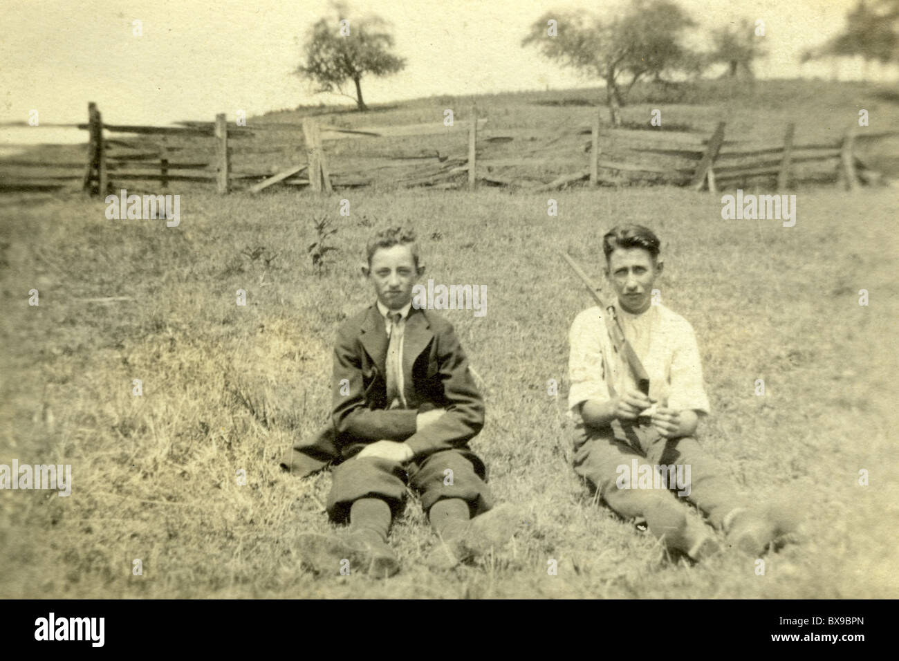 Due cacciatori all'aperto farm staccionata in legno ragazzi giovani uomini fratelli fucile da caccia azione di vite americana in bianco e nero Foto Stock