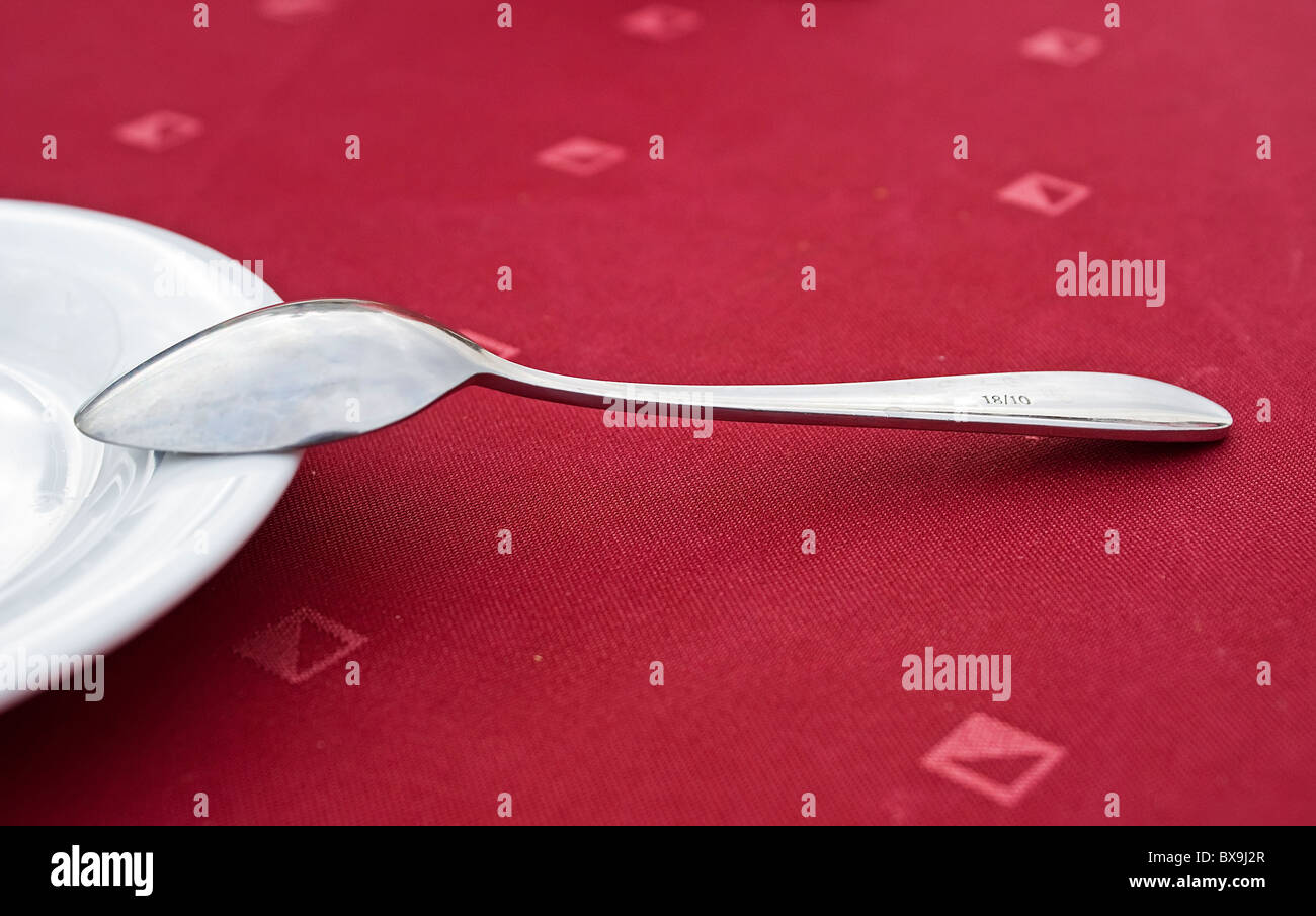 Cucchiaio da tè sul tavolo ricoperto da un panno rosso Foto Stock