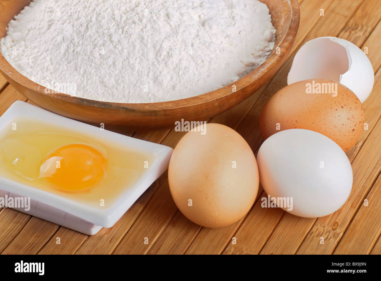 La farina con le uova di greggio per produrre un impasto Foto Stock