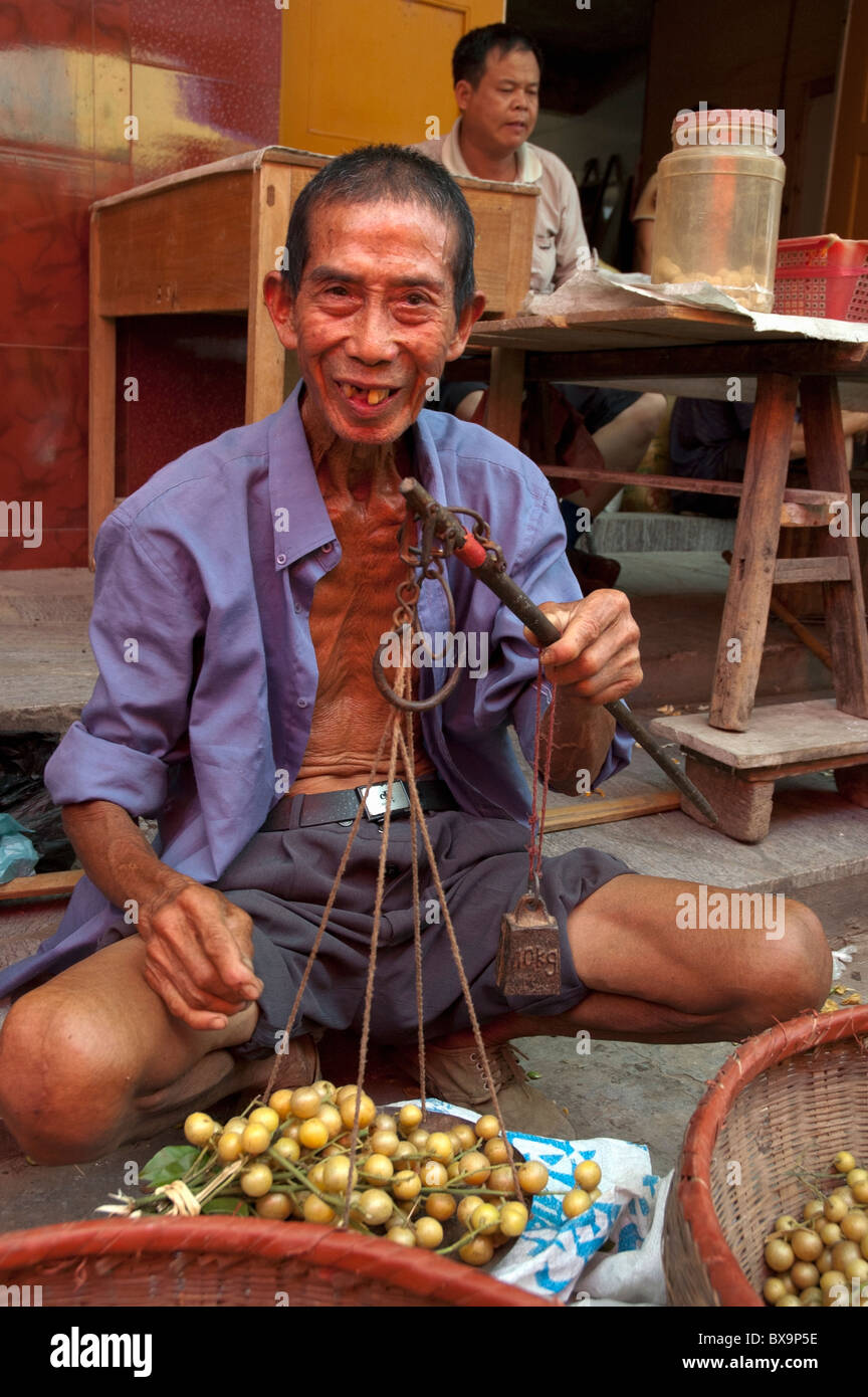 L'uomo vendita di uva gialli al settimanale mercato alimentare nel villaggio Fuli, Yangshuo, Guangxi, Cina. Foto Stock
