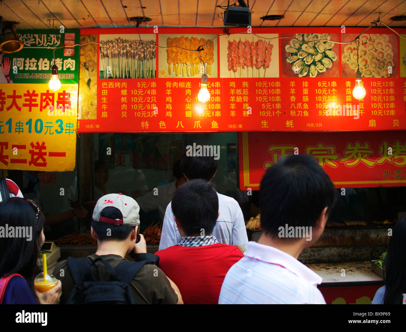 Una coda di cittadini cinesi di attendere per il fast food da un prodotto alimentare stallo in una stradina di Pechino Foto Stock