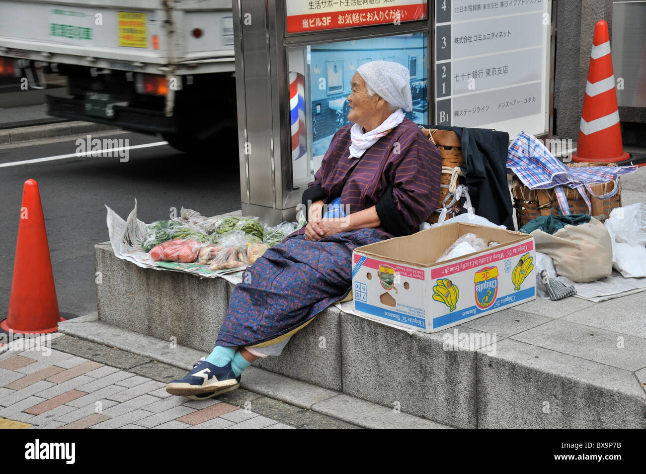 Vecchia donna vending ortaggi in street, Ginza, Tokyo, Giappone Foto Stock