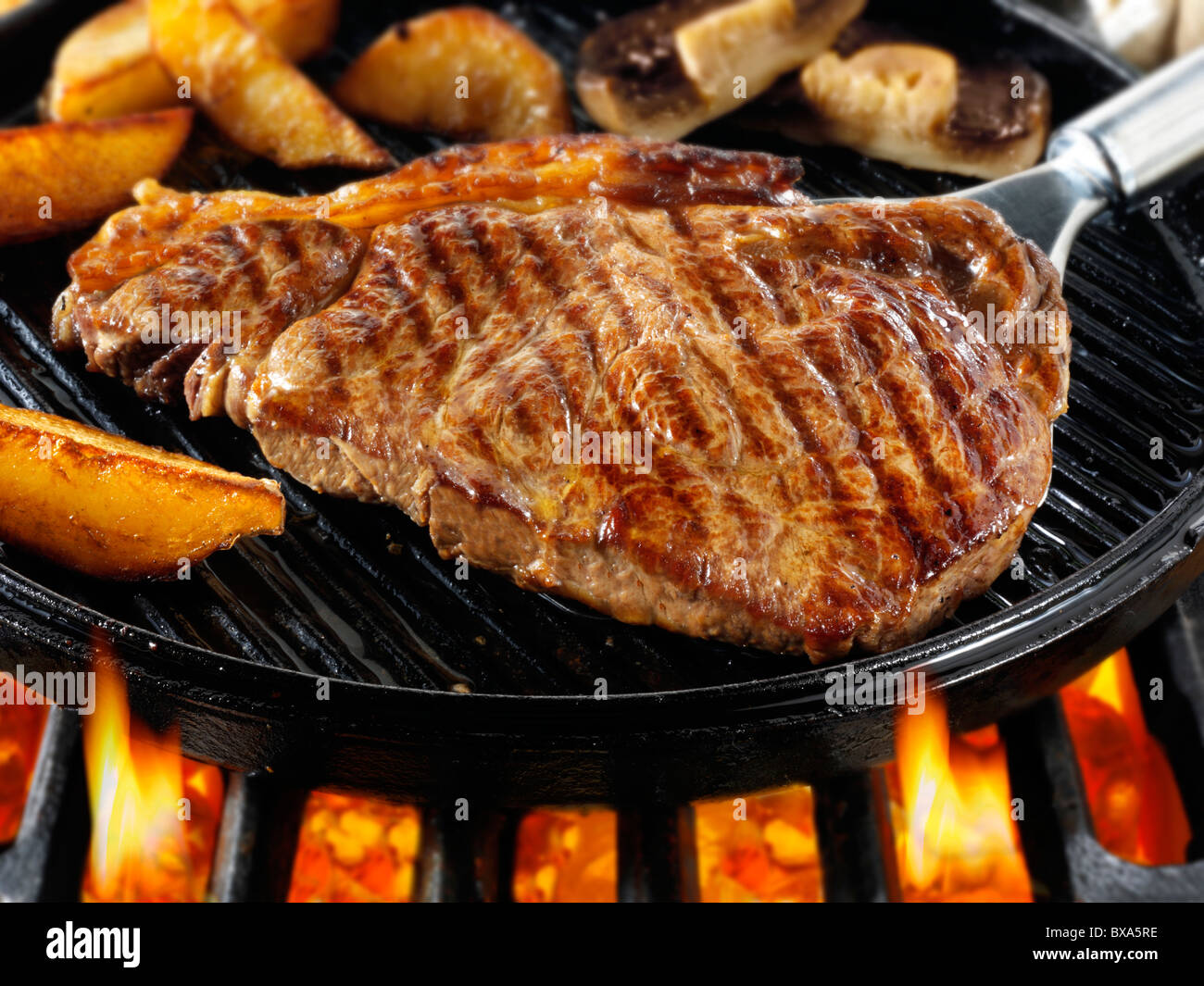 Lombata di manzo bistecche e patatine fritte in padella fritto su un barbecue. Alimenti a base di carne le foto, foto e immagini. Foto Stock