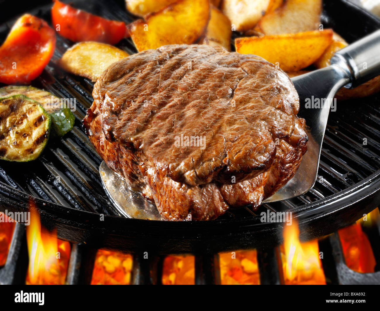 Filetto di manzo bistecche, patatine arrosto & p[eppers essendo pan fried su un barbecue. Alimenti a base di carne le foto, foto e immagini. Foto Stock