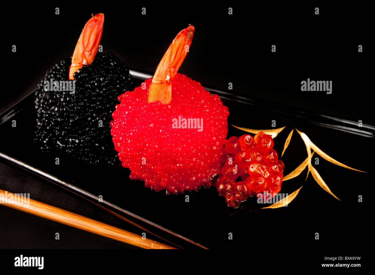 Sushi Norimaki coperto di rosso e nero uova di pesce con code di gamberi. Foto Stock