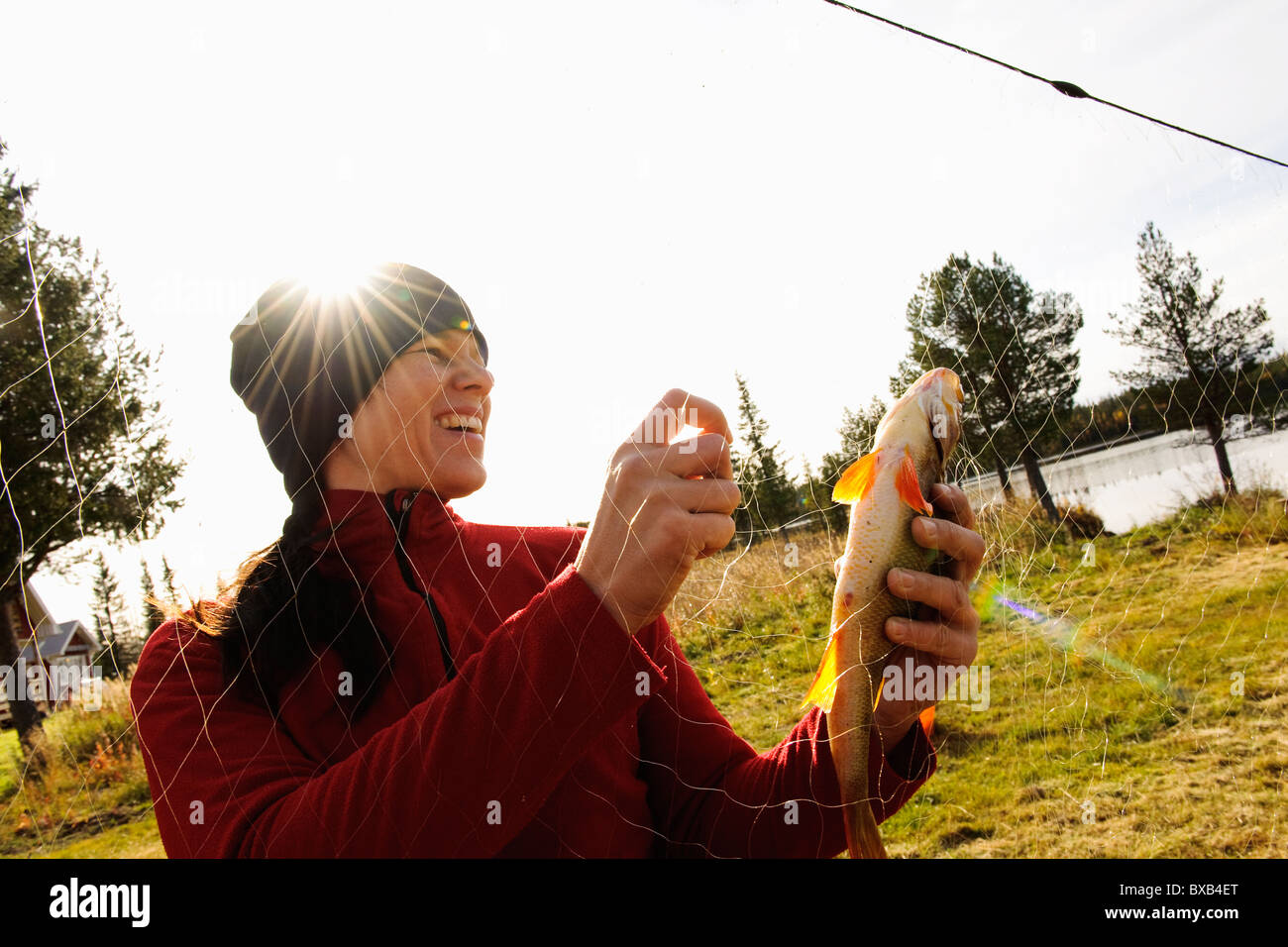 Donna di prendere il pesce dalla rete da pesca Foto Stock