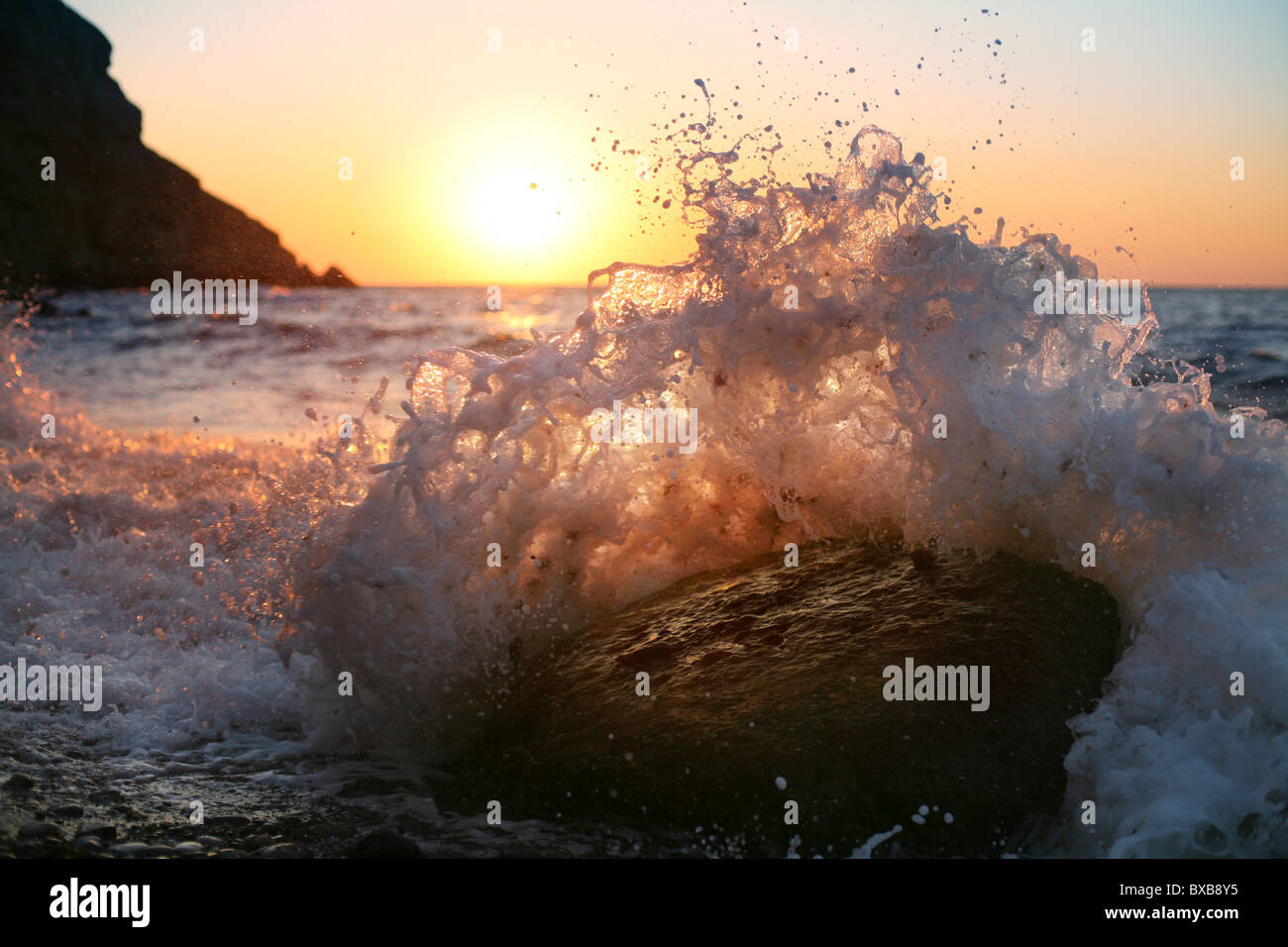 All'alba, le onde infrangersi sulla pietra Foto Stock