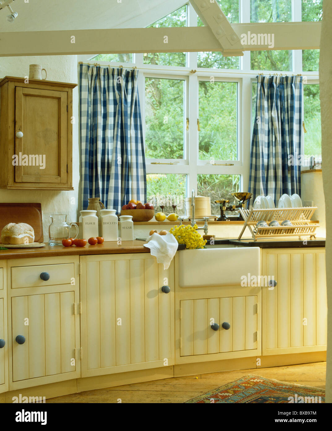 Blue+bianco tende selezionata sulla finestra sopra il lavabo in cottage  estensione da cucina con un pallido giallo unità montata Foto stock - Alamy