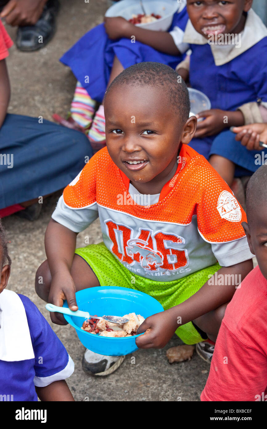 Ragazzo di mangiare cibo fornito a Maji Mazuri scuola nella baraccopoli di Mathare, Nairobi, Kenia Foto Stock