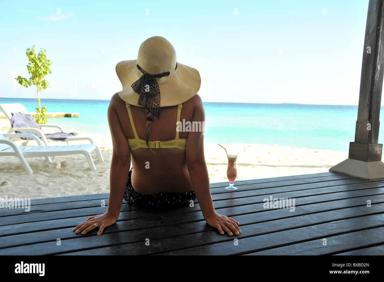 La donna seduta sul decking in Maldive Foto Stock