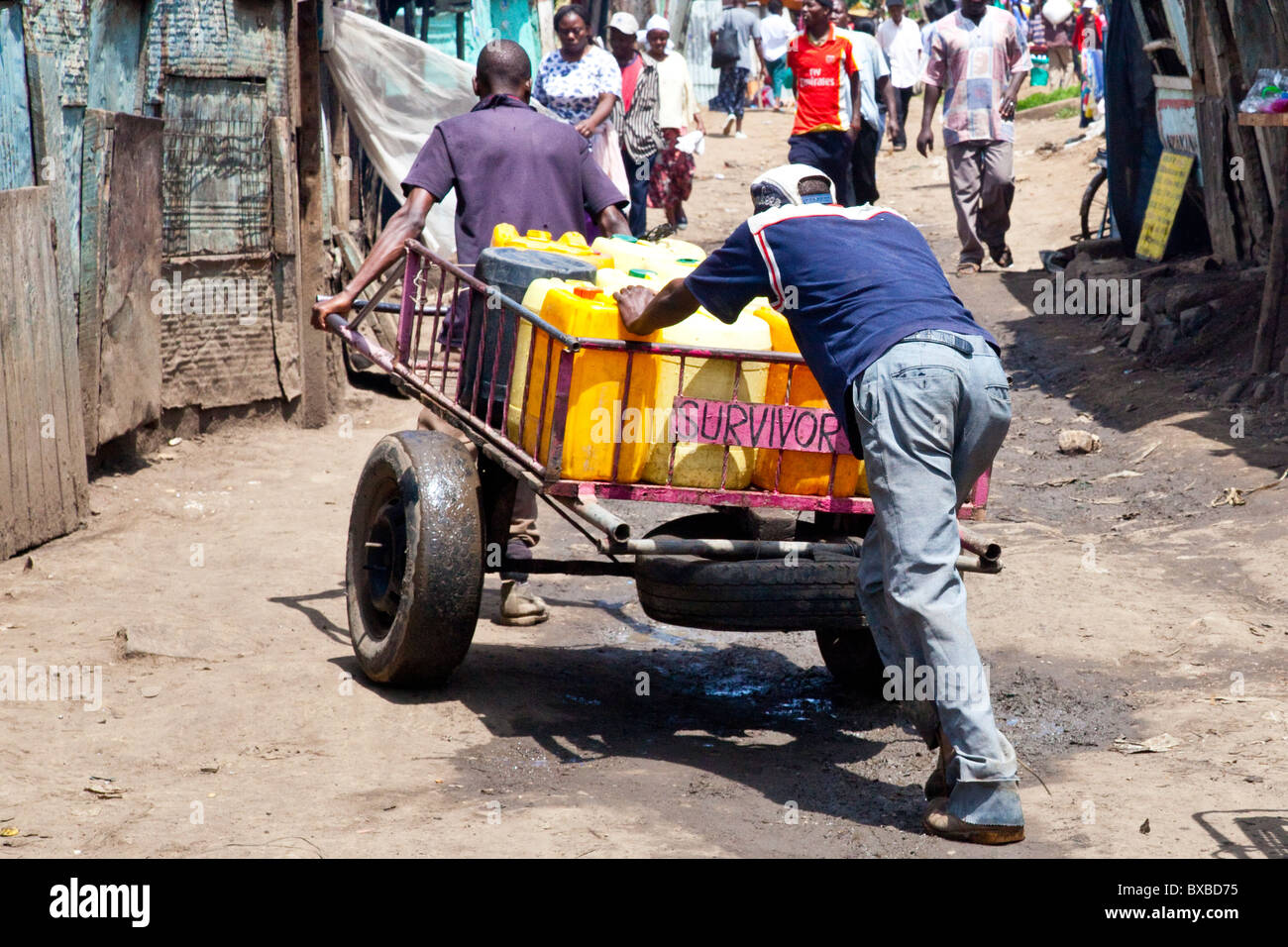 Gli uomini di spingere i contenitori di acqua fresca attraverso il Mathare slum di Nairobi, in Kenya Foto Stock