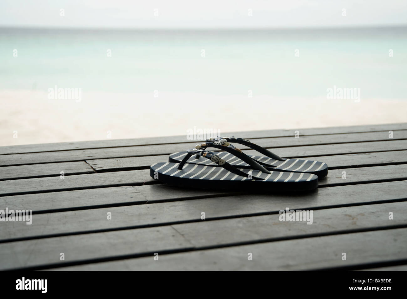 Flip-flop sul legno decking in Maldive Foto Stock