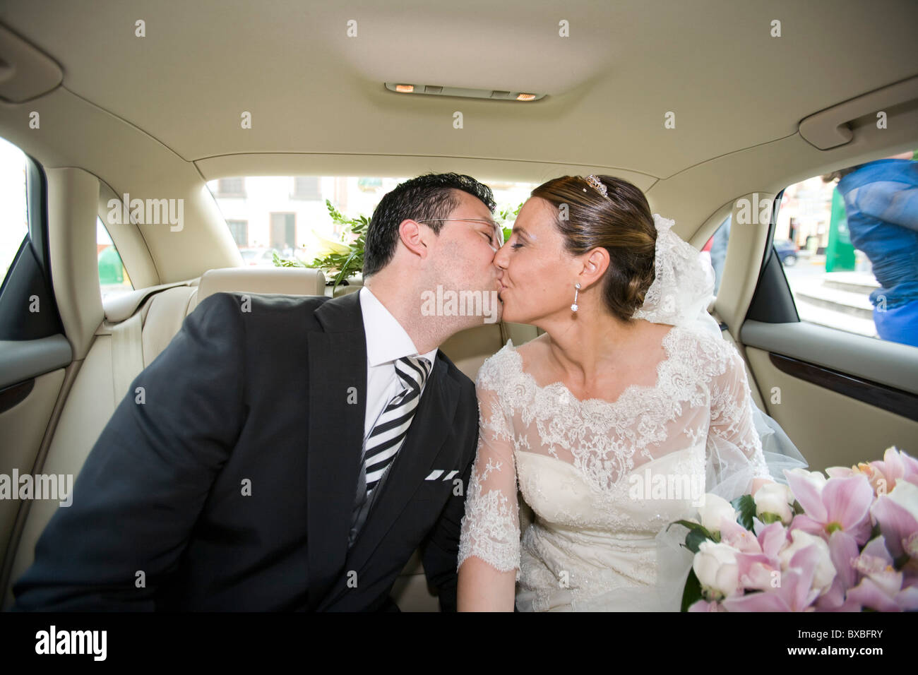 Una coppia di novelli sposi baciare in una macchina Foto Stock