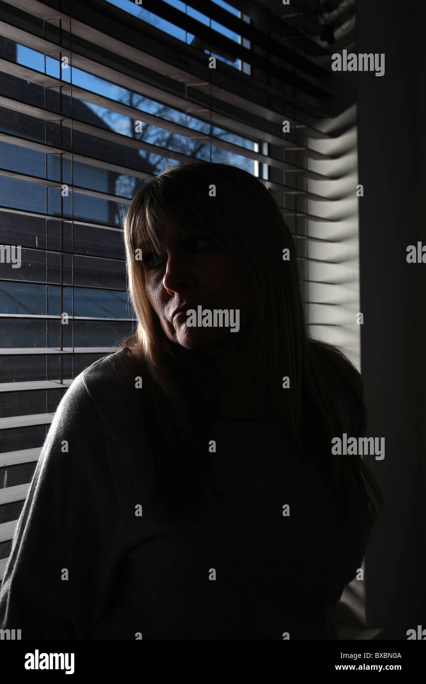 Ritratto di una bionda donna che guarda fuori da una finestra, premuto Foto Stock