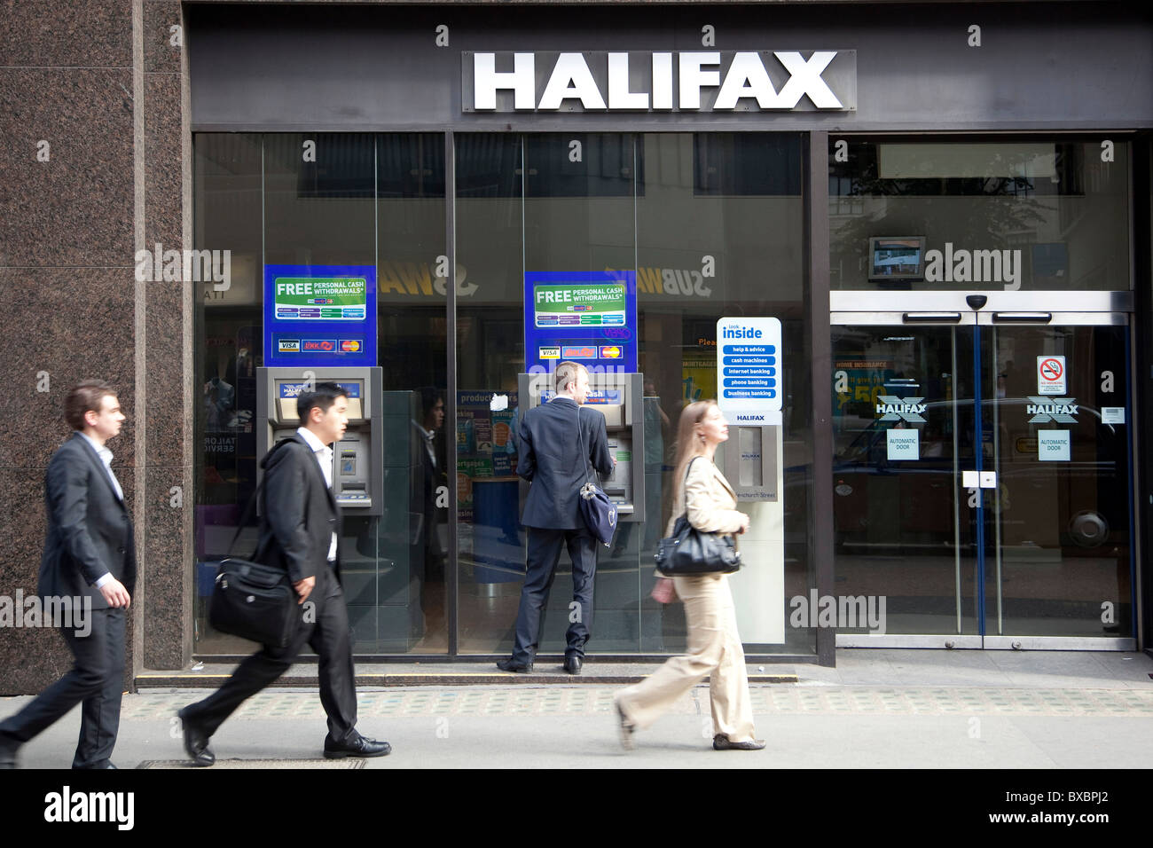 I passanti presso bancomat di Halifax Bank in London, England, Regno Unito, Europa Foto Stock