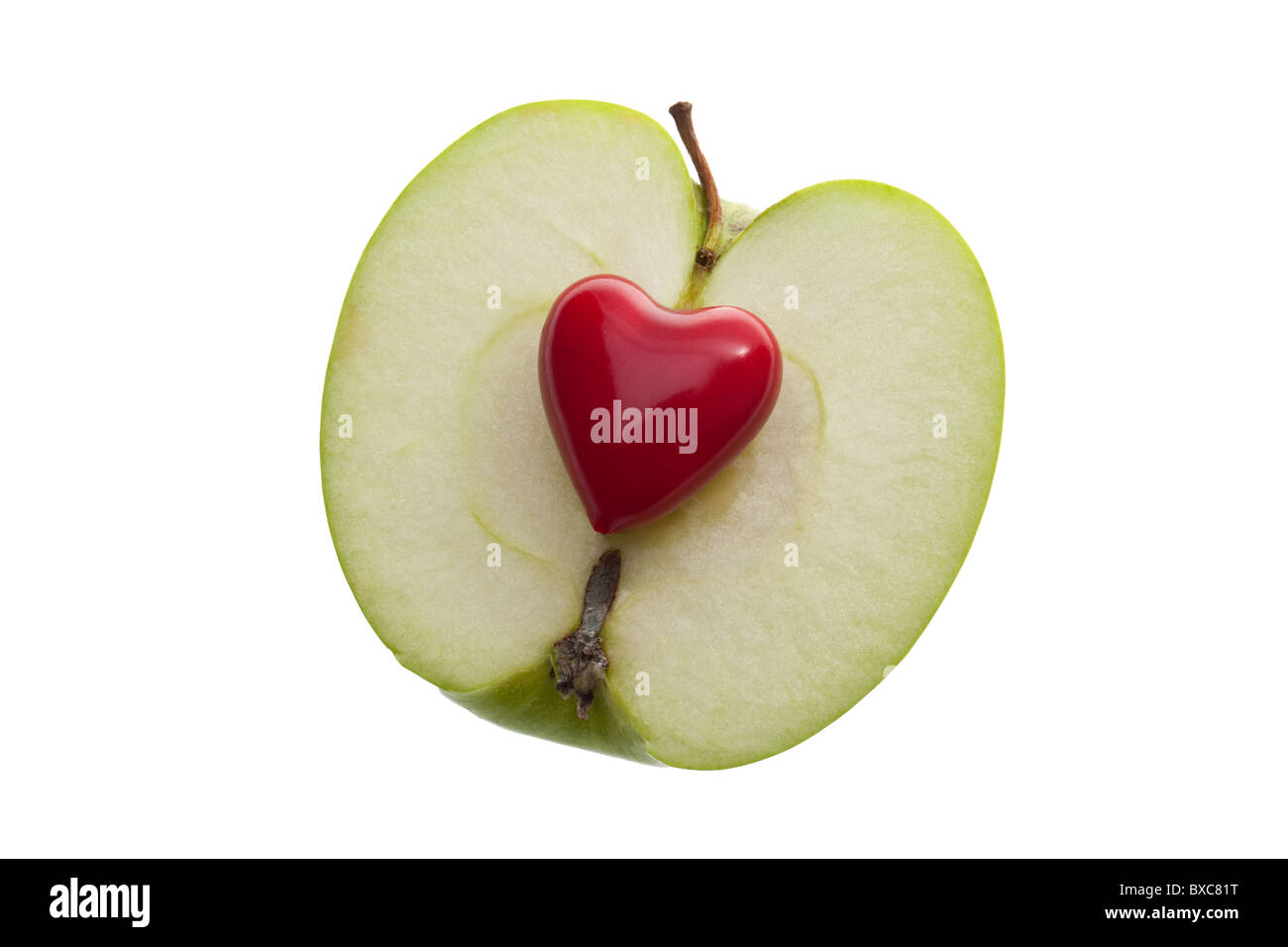 Un piccolo cuore rosso su uno fette di mela verde su un bianco sfondo senza giunture Foto Stock