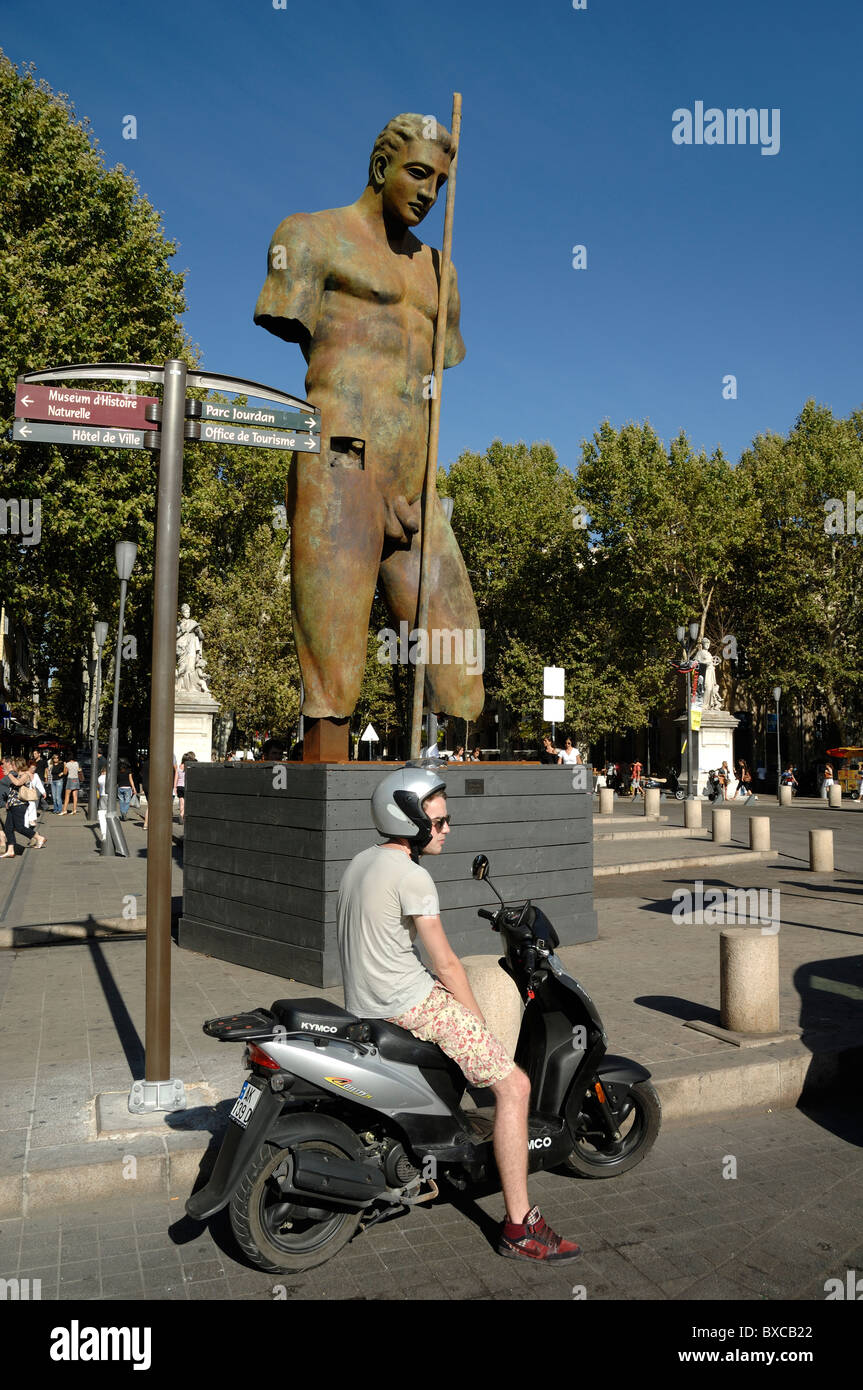 Statua gigante e giovane uomo in attesa in scooter a la Rotonde, Cours Mirabeau, Aix-en-Provence o Aix en Provence, Francia Foto Stock
