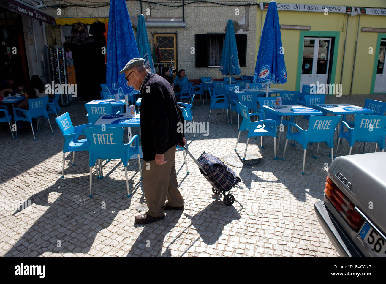 Un uomo vecchio attraversando una piazza di Olhao, Portogallo Foto Stock