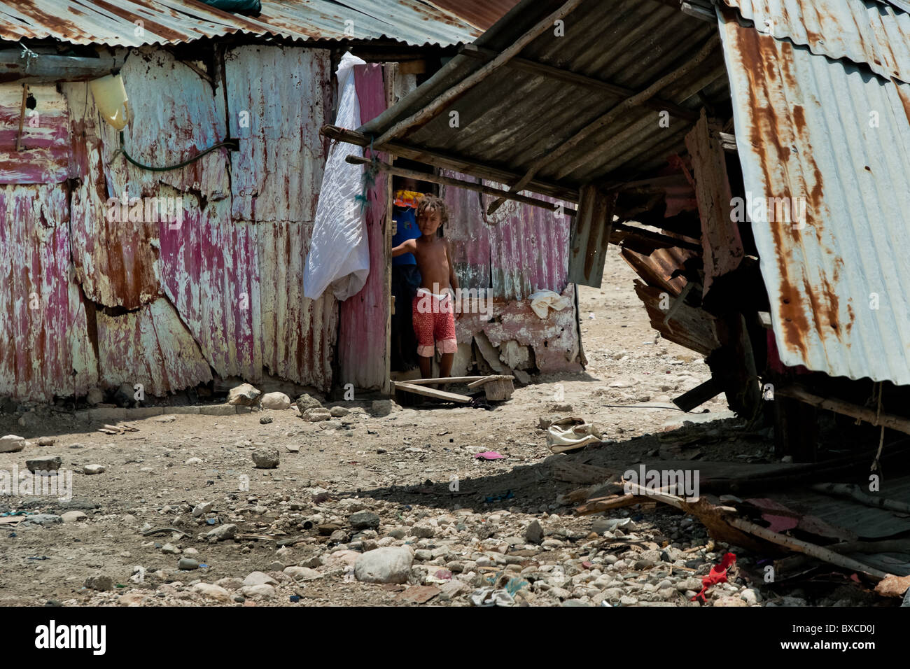 Ragazza haitiana sta nella porta di una baracca nella baraccopoli di cité soleil. Foto Stock