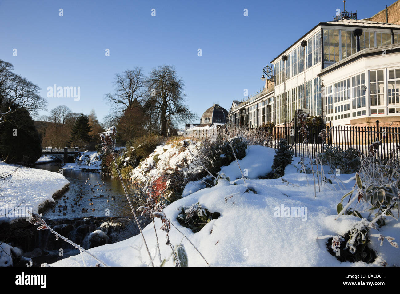 Buxton, Derbyshire, Inghilterra, Regno Unito, Europa. Padiglione e il Pavilion Gardens fiume con la neve in inverno Foto Stock